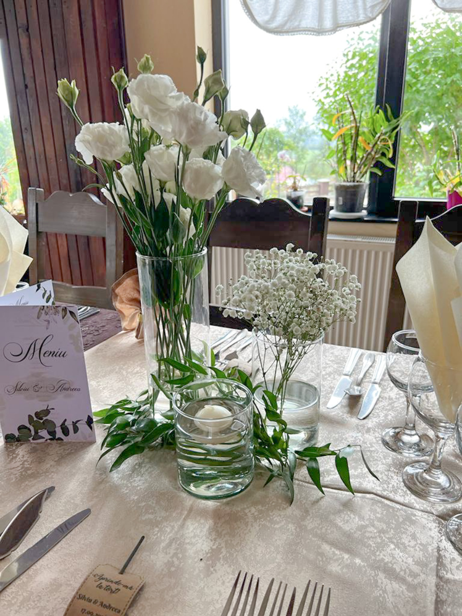 Aranjament floral alb cu vaze și meniu pe masa de eveniment