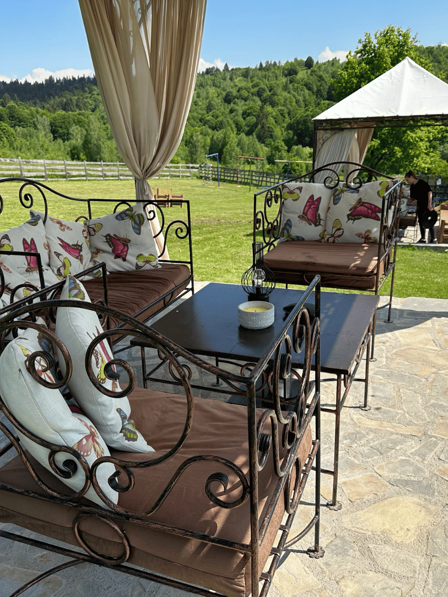 Lounge pe terasă cu perne și vedere spre dealurile verzi din Întorsura Buzăului
