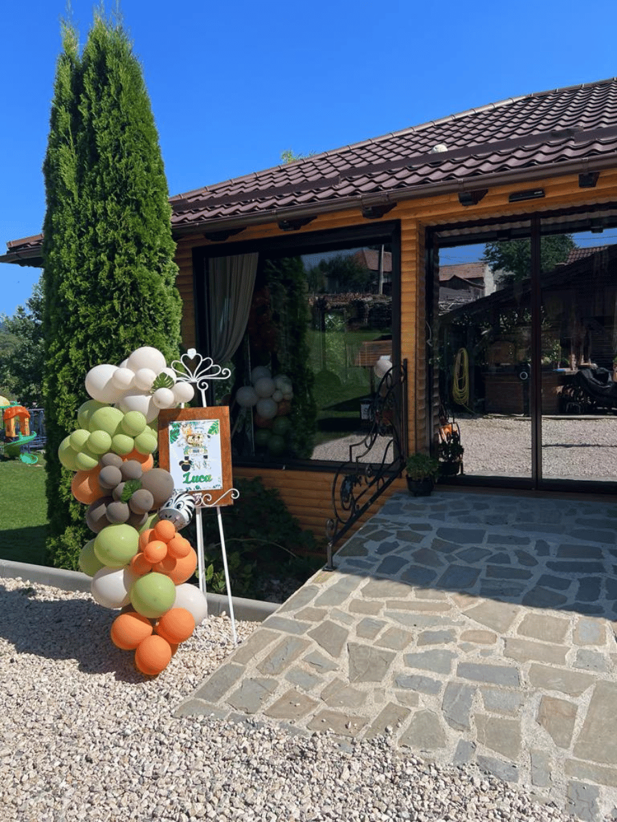 Foișor de lemn cu arcadă de baloane și panou de eveniment la intrare