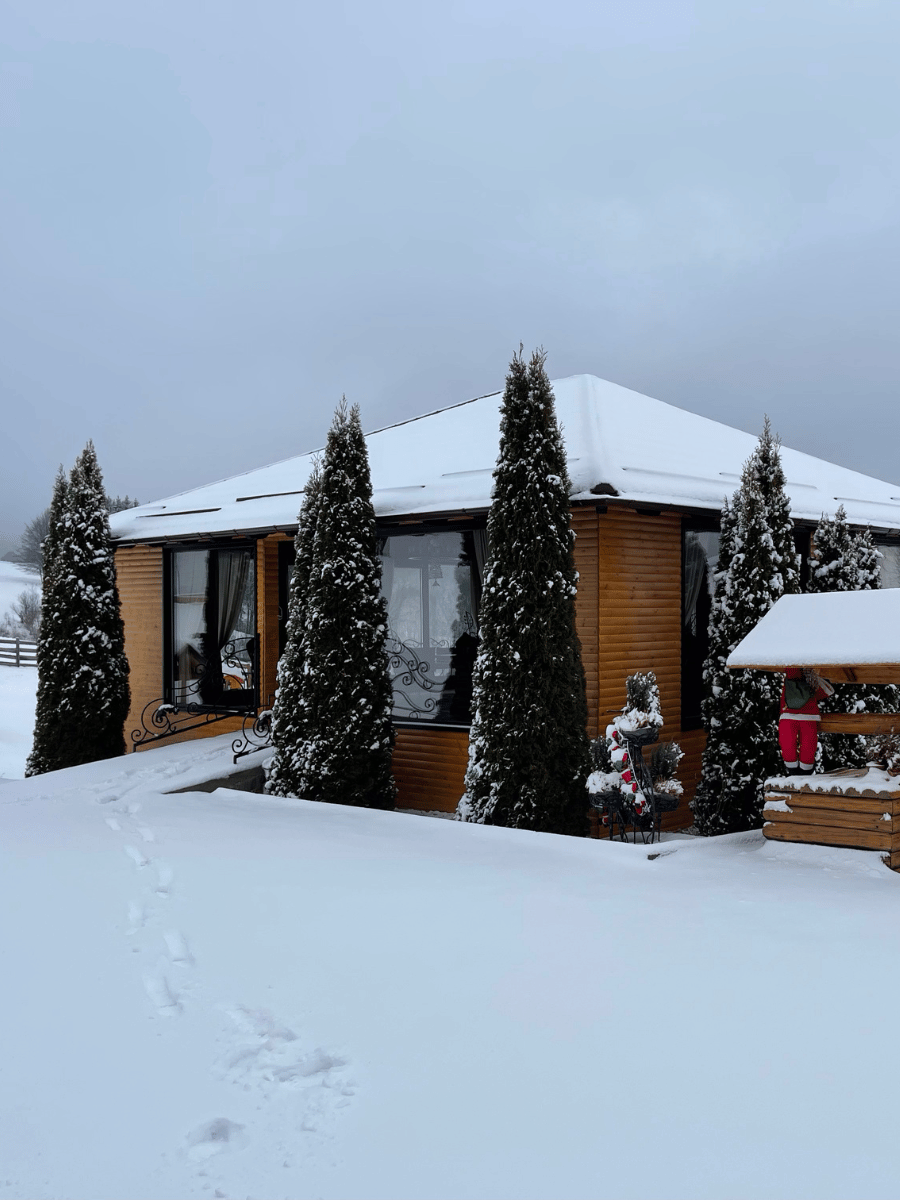 Foișor închis acoperit de zăpadă, cu tuia și fântână decorativă la Casa Brădet