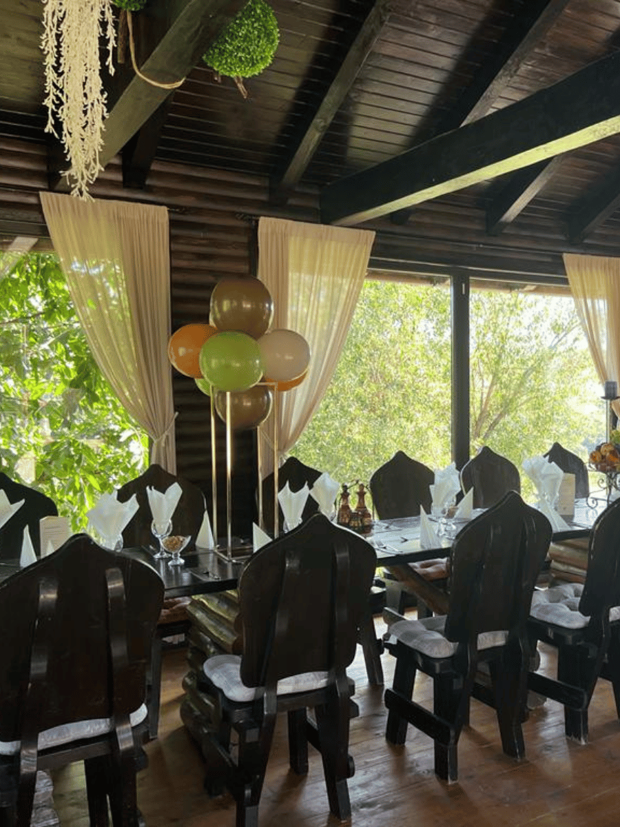 Interior foișor cu masă lungă de lemn și decor din baloane la Casa Brădet
