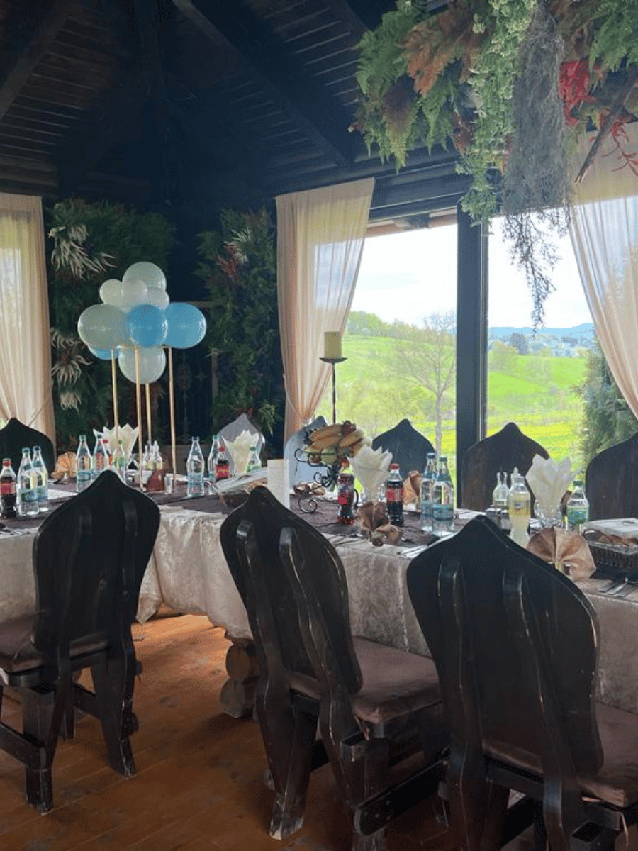 Masă de eveniment cu baloane alb-bleu și vedere spre dealurile din Covasna