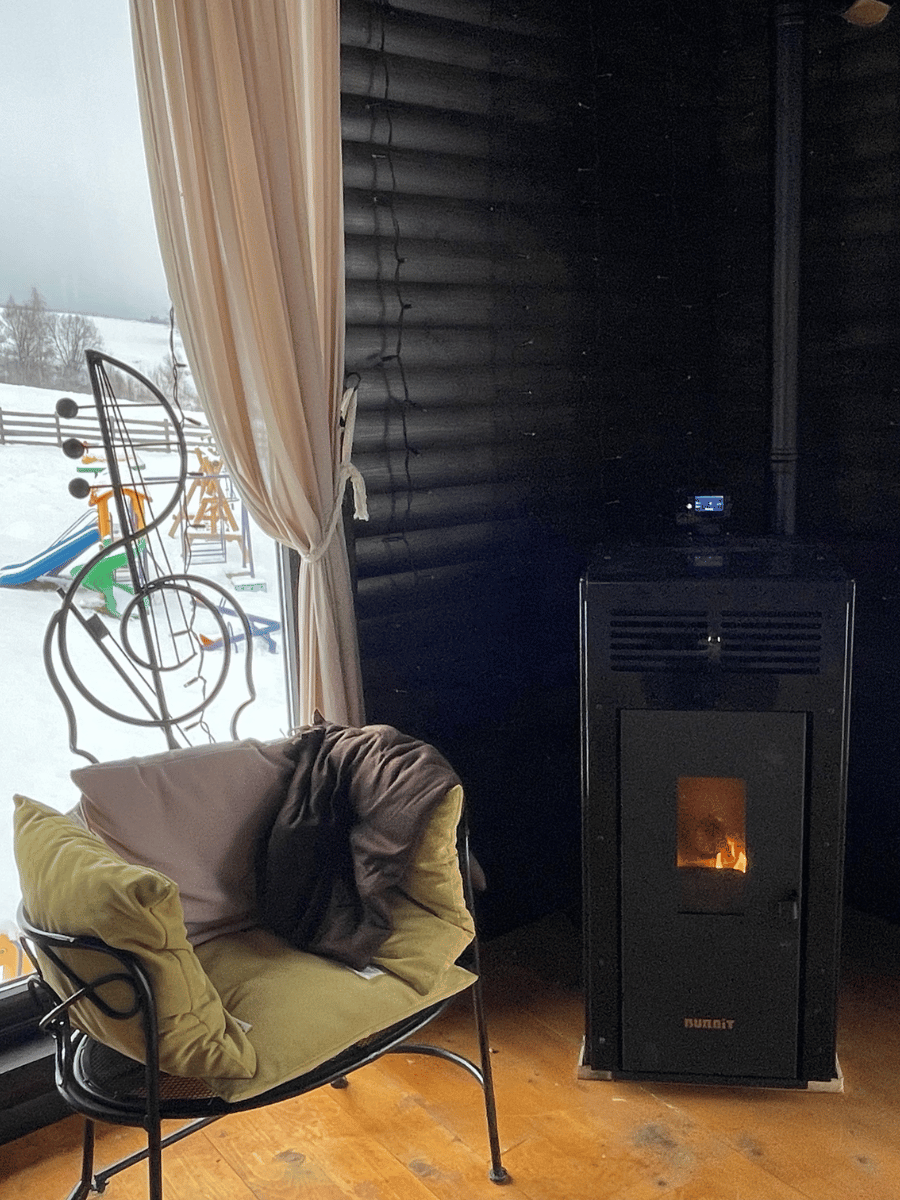 Colț cald cu sobă pe pelete și vedere spre locul de joacă iarna