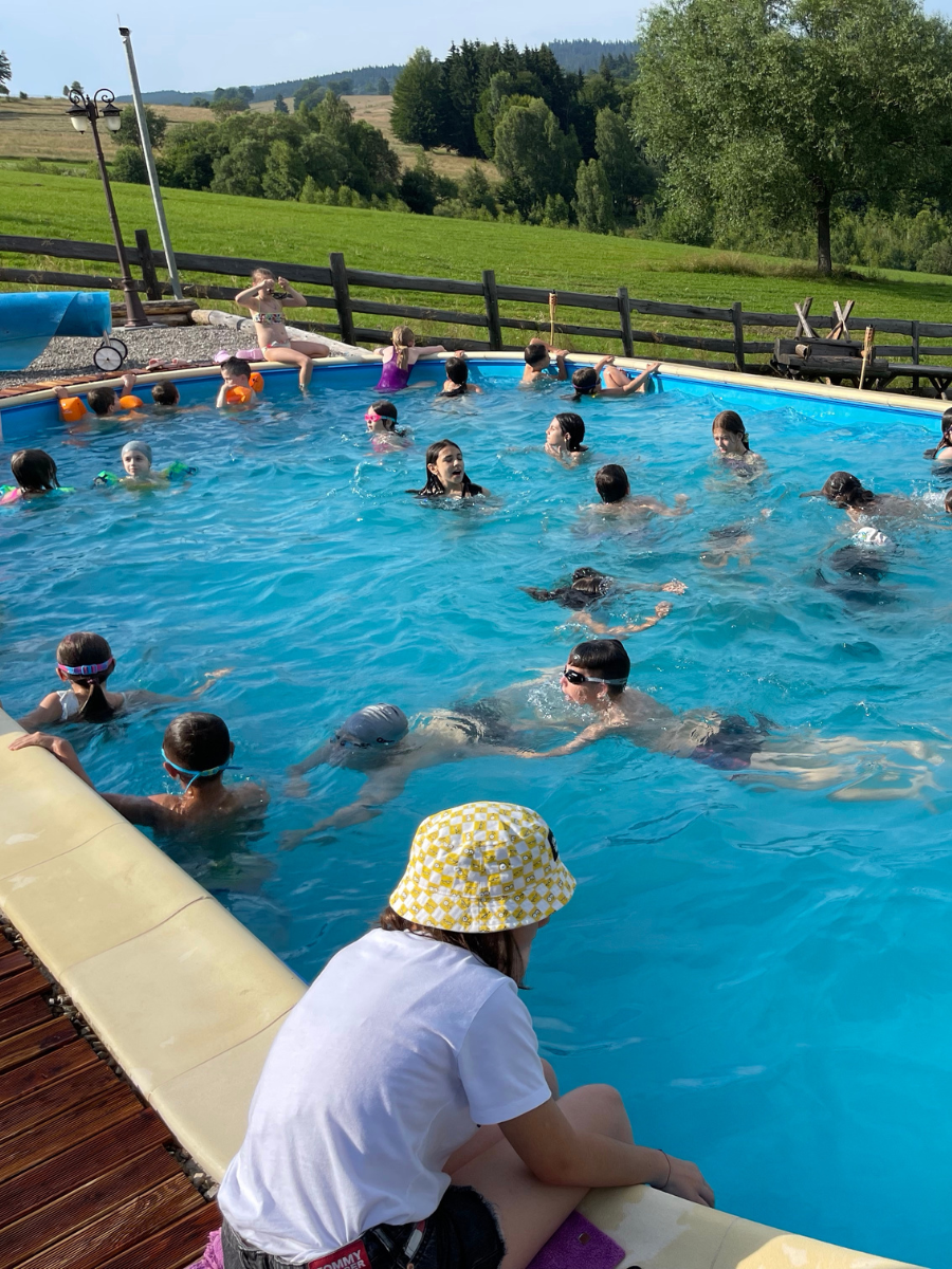 Copii înotând în piscina exterioară, peisaj verde în Covasna