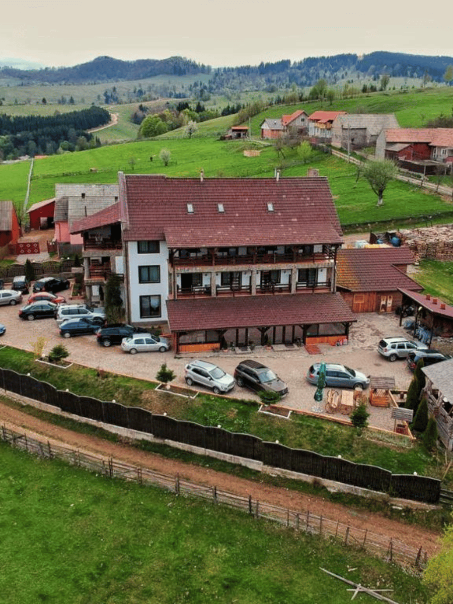 Vedere aeriană a pensiunii Casa Brădet pe dealuri verzi, cu parcare și păduri în Întorsura Buzăului, Covasna