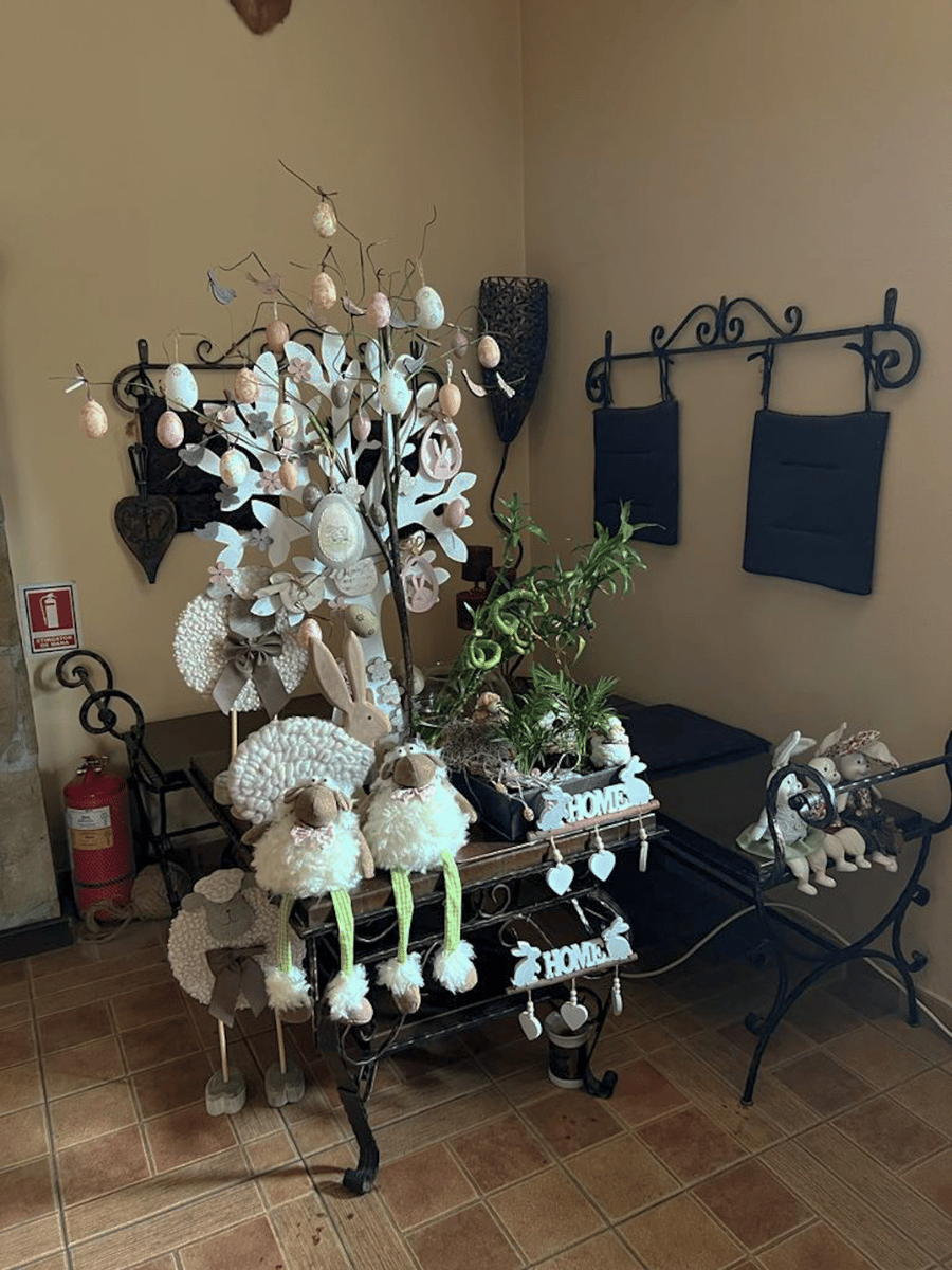 Decor de Paște pe masă de fier forjat, cu ouă pastel, miei de pluș și iepurași la Casa Brădet