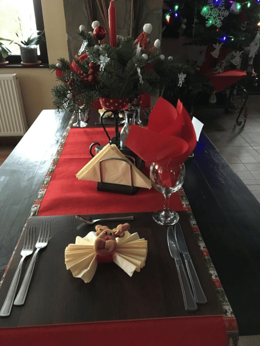 Masă de restaurant pregătită de Crăciun, cu șervețel cu ren și brad luminat