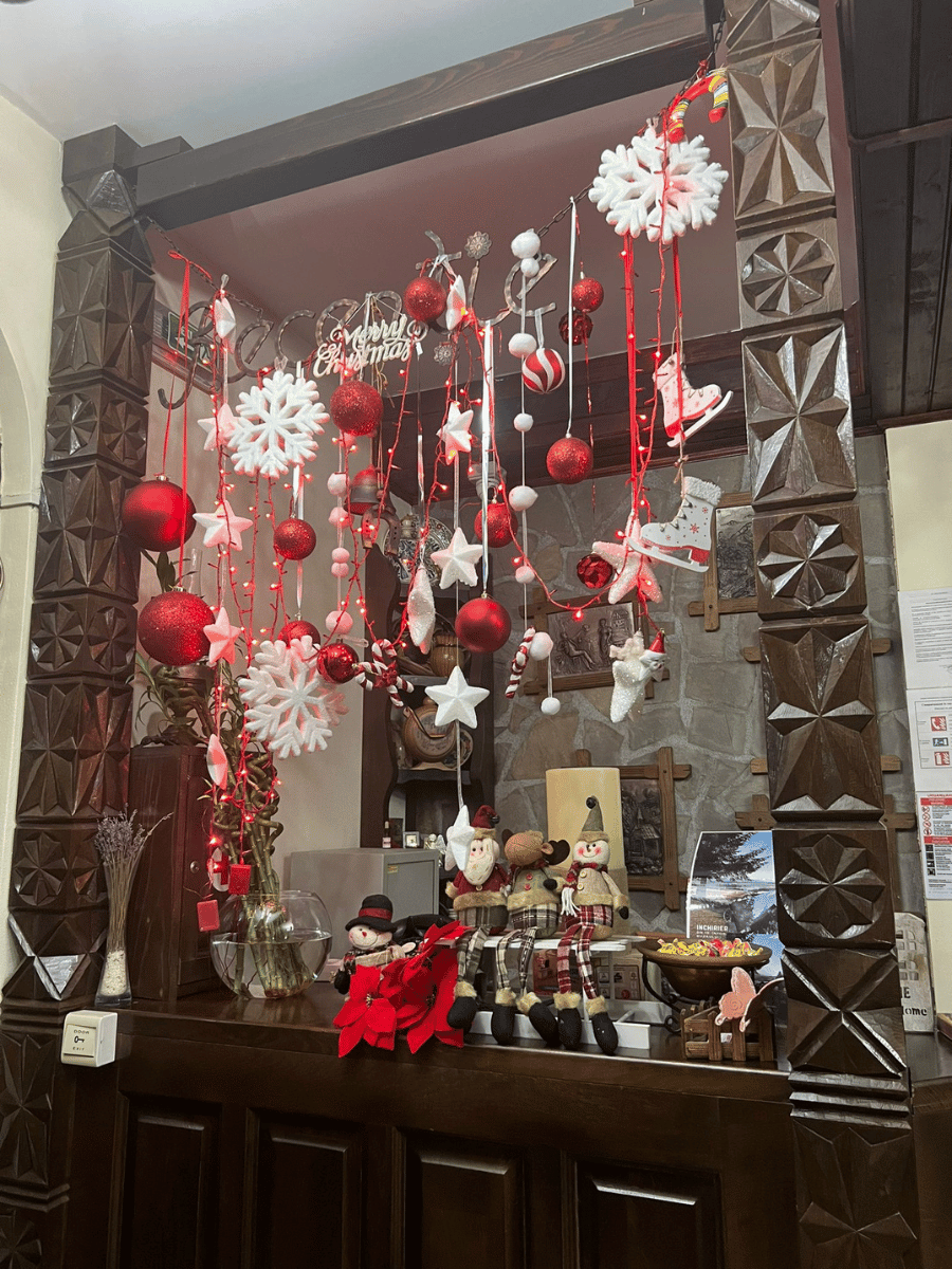 Recepție festivă între stâlpi sculptați, cu figurine de Crăciun pe tejghea