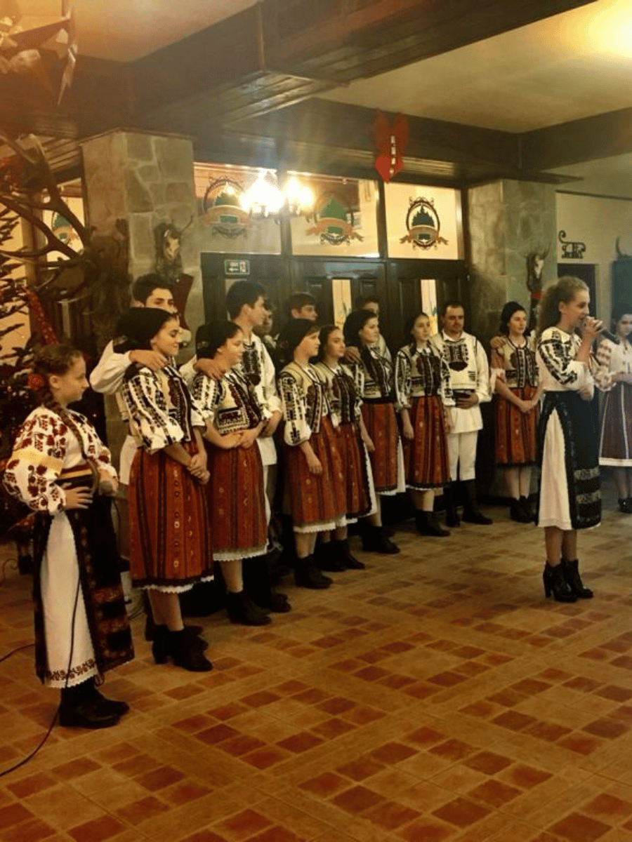 Copii în costume populare cântând la evenimentul de iarnă din restaurant
